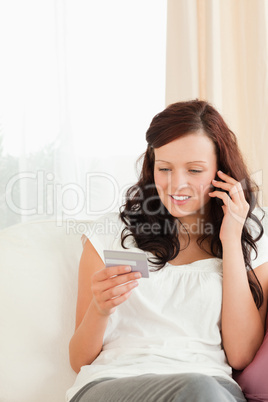 Young woman looking at her credit card holding phone