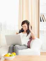 Gorgeous woman listening to music with a laptop on her lap