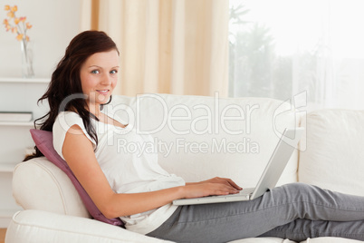 Smiling Woman with a laptop lying on a sofa