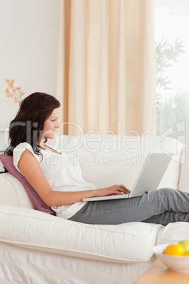 Gorgeous red-haired woman with a notebook sitting on a sofa