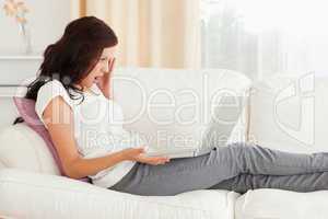 Amazed woman with a notebook on a sofa