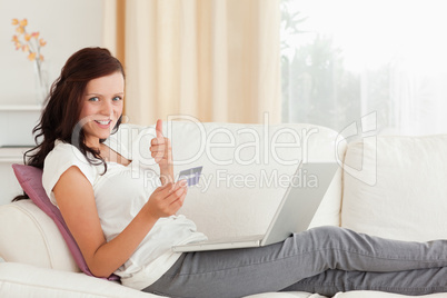 Woman with laptop and credit card holding thumb up