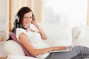 Joyful woman with headphones and a laptop looking into the camer