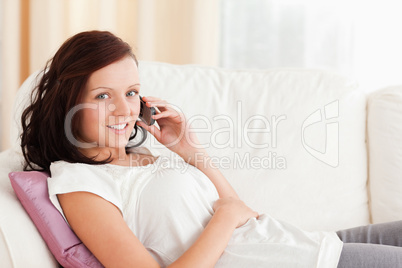 Woman sitting on a sofa with a phone looking at the camera