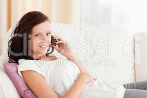 Woman sitting on a sofa with a phone looking at the camera
