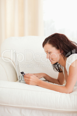 Joyful woman working on notebook with credit card in hand