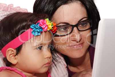 Small girl and mother with laptop at home