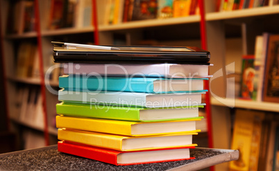 Stack of colorful books with electronic book reader