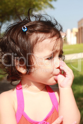Little baby girl, sucking her thumb walking in the park