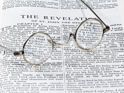 Antique reading glasses on page of bible