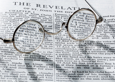Antique reading glasses on page of bible