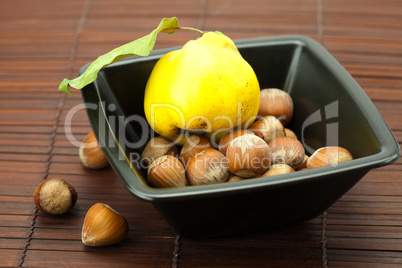 hazelnuts in a bowl and quinces on a bamboo mat