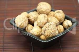 walnuts in a bowl on a bamboo mat