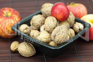 walnuts and apples in a bowl on a bamboo mat