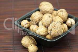 walnuts in a bowl on a bamboo mat