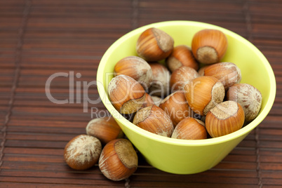 hazelnuts in a bowl on a bamboo mat