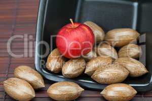 pecans and apples in a bowl on a bamboo mat