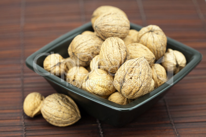 walnuts in a bowl on a bamboo mat