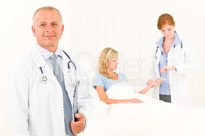 Two doctors with patient lying in bed