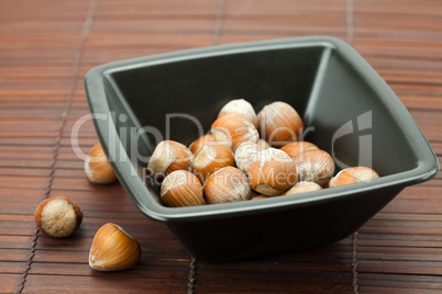 hazelnuts in a bowl on a bamboo mat