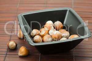 hazelnuts in a bowl on a bamboo mat