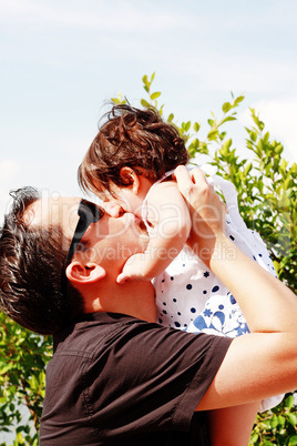 father in early thirties gives his son a kiss on the cheek in th