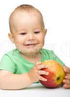 Little child is biting red apple