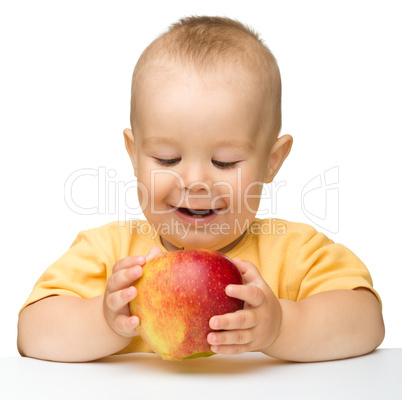 Little child is biting red apple