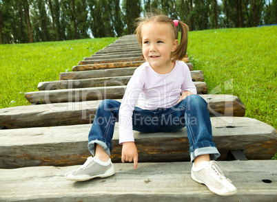 Cute little girl is sitting on stairs