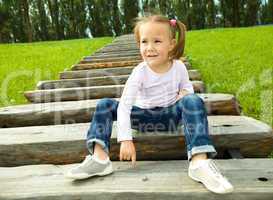 Cute little girl is sitting on stairs