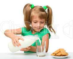 Cute little girl is pouring milk in glass