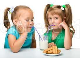 Two little girls are drinking milk
