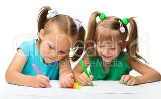 Two little girls draw with markers