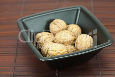 walnuts in a bowl on a bamboo mat