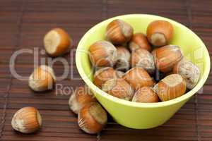 hazelnuts in a bowl on a bamboo mat