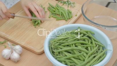 CLIP EDIT Chopping string green beans into three parts on wooden board