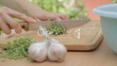 CLIP EDIT Chopping fresh green beans on wooden cutting board outdoors