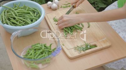 Trimming French green beans on wooden chopping board outdoors