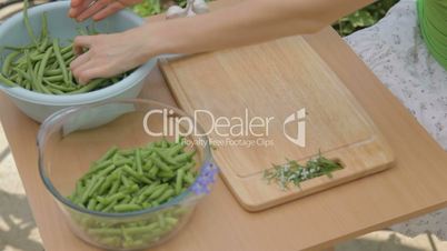Preparing young green bunch of beans for slicing outdoors