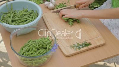 Carving fresh green beans outdoors on wooden chopping board