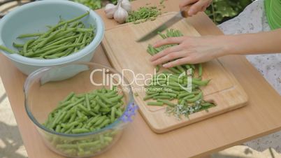 French green beans being cut on wooden chopping board outdoors