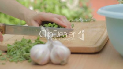 Carving fresh green beans outdoors on wooden chopping board