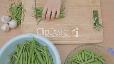 Trimming young green beans, cutting on wooden chopping board