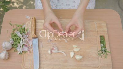 Shucking garlic cloves from dry skins on wooden board outdoors