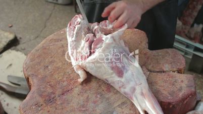 Butcher separating bone from pulp on mutton's leg
