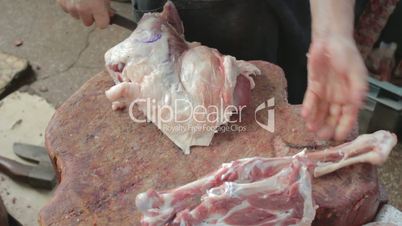 Butcher chopping bones of mutton leg with axe