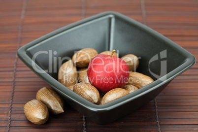 pecans and apples in a bowl on a bamboo mat