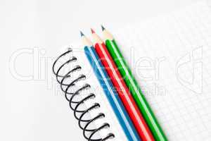 colored pencils and a notebook isolated on white
