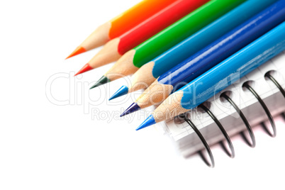 colored pencils and a notebook isolated on white