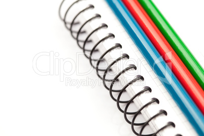 colored pencils and a notebook isolated on white